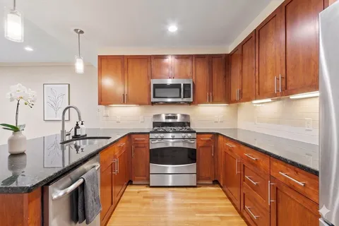 a kitchen with stainless steel appliances granite countertop a sink stove and cabinets
