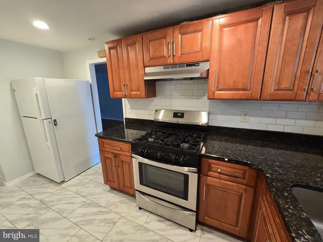 a kitchen with granite countertop a refrigerator stove and cabinets