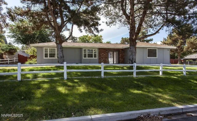 a view of a house with a yard and a large tree