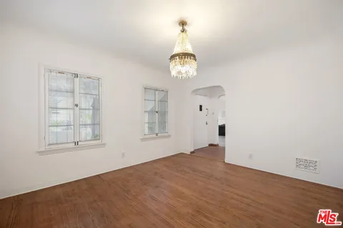 an empty room with wooden floor cabinet and windows