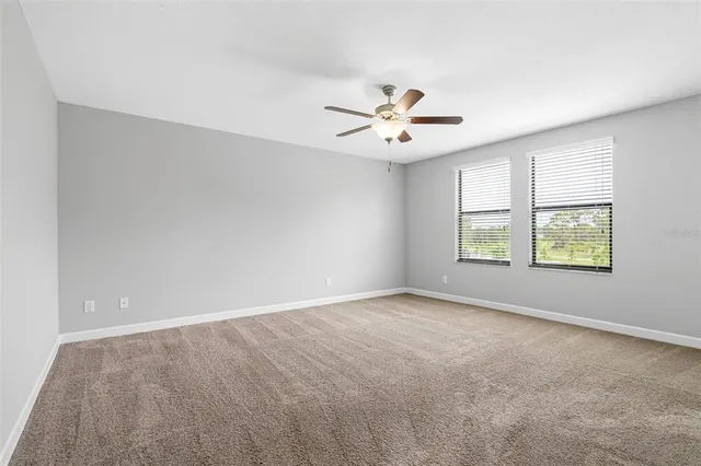 an empty room with windows and ceiling fan