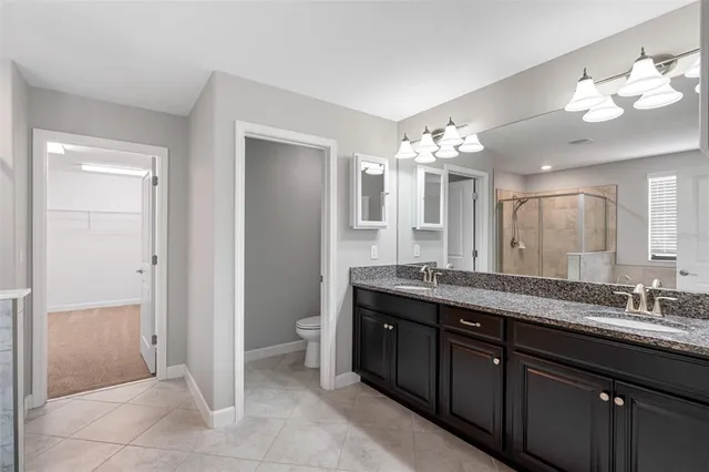 a spacious bathroom with a granite countertop sink a toilet and a mirror