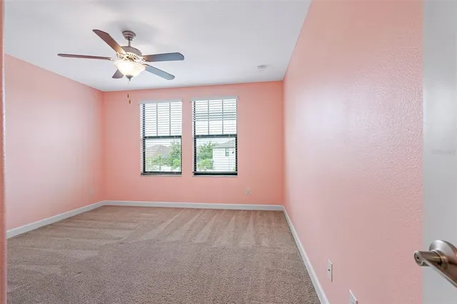 an empty room with windows and fan