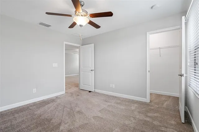 an empty room with closet and a chandelier fan