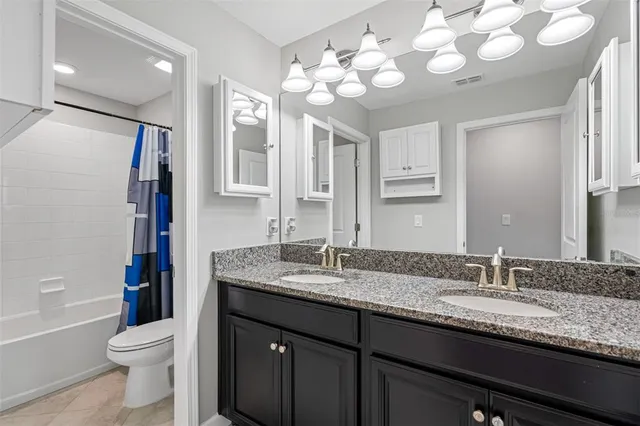 a bathroom with a granite countertop sink a toilet and a large mirror