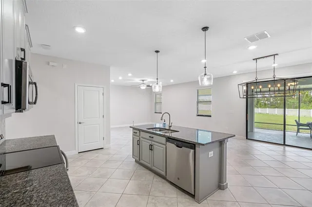 a kitchen with stainless steel appliances granite countertop a sink a counter space and a window