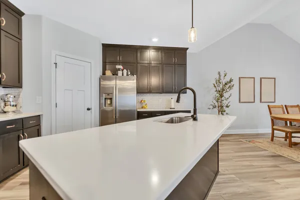 a large white kitchen with sink and stainless steel appliances
