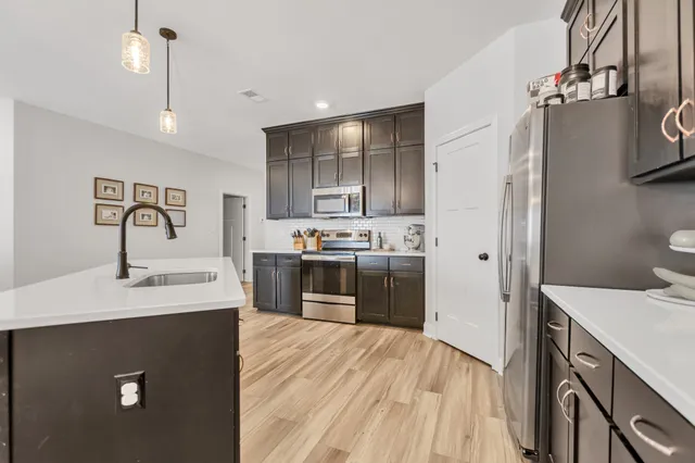 a kitchen with kitchen island a sink appliances and cabinets