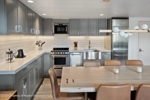 a kitchen with kitchen island a stove a table and chairs
