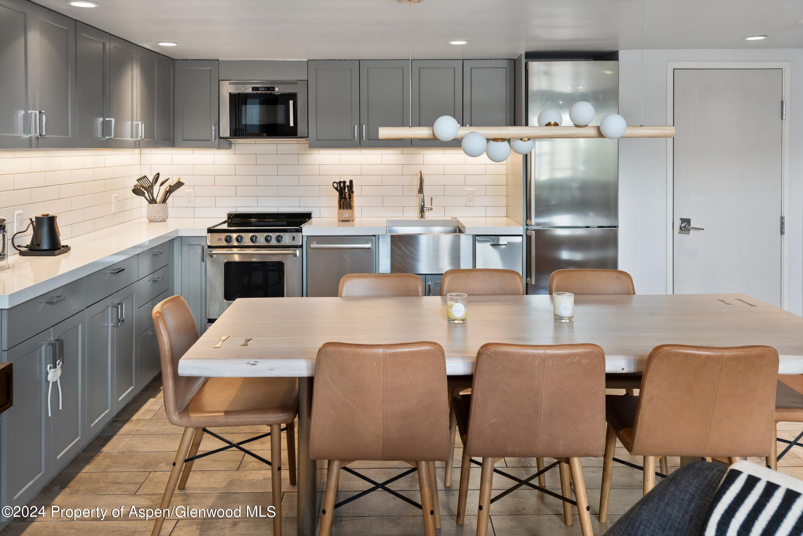 800 South Mill Street, Unit 102C Aspen, CO 81611 - Photo 9 of 23 a kitchen with stainless steel appliances kitchen island granite countertop a table chairs microwave and sink
