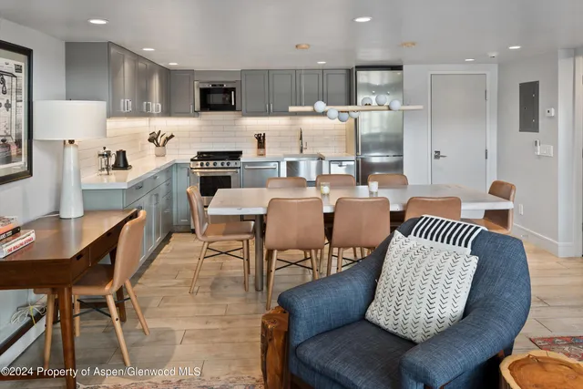 a kitchen with stainless steel appliances granite countertop a sink a stove a refrigerator cabinets and chairs