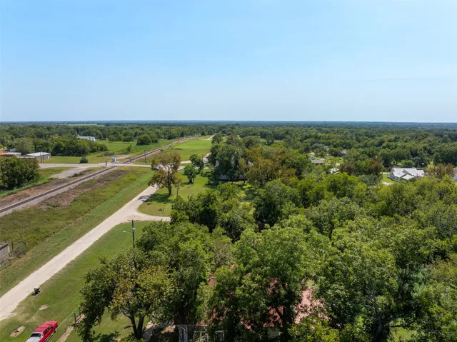 an aerial view of residential houses with outdoor space and trees