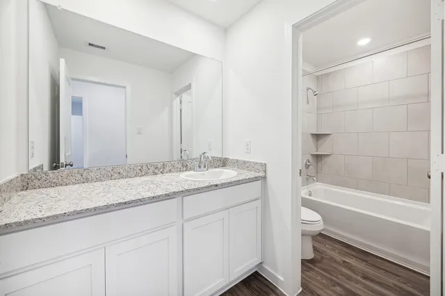 a bathroom with a granite countertop sink a toilet and bathtub