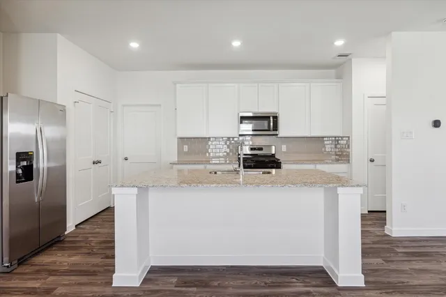 a kitchen with stainless steel appliances granite countertop a refrigerator a stove and a sink