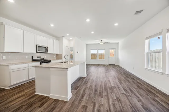 a kitchen with wooden floors and white cabinets