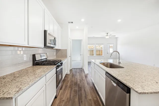 a kitchen with stainless steel appliances granite countertop a sink stove and cabinets