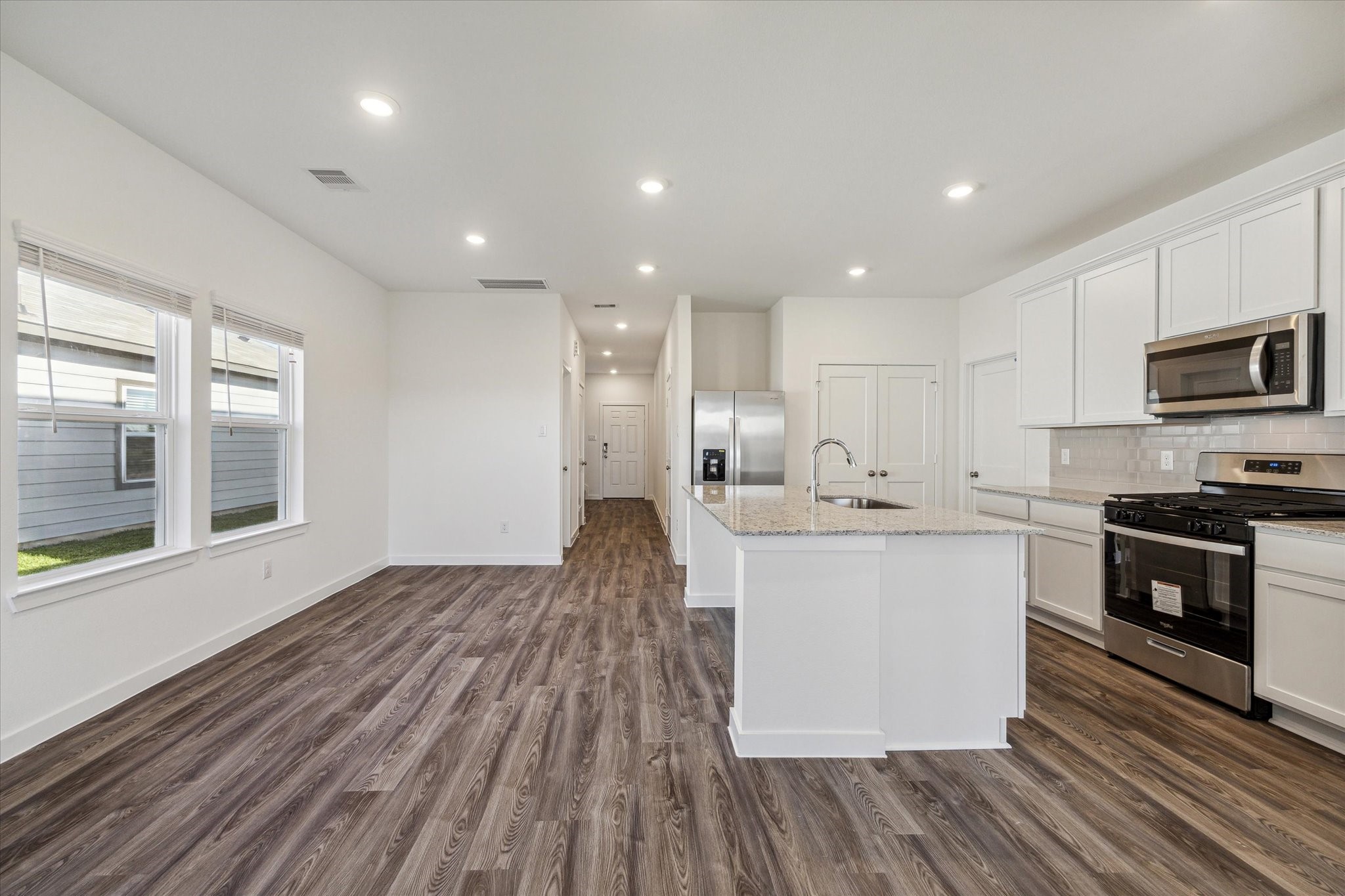 3926 Glory Grn Drive Brookshire, TX 77423 - Photo 8 of 21 a large kitchen with stainless steel appliances a large counter top a stove a sink dishwasher a refrigerator and a microwave oven with wooden floor
