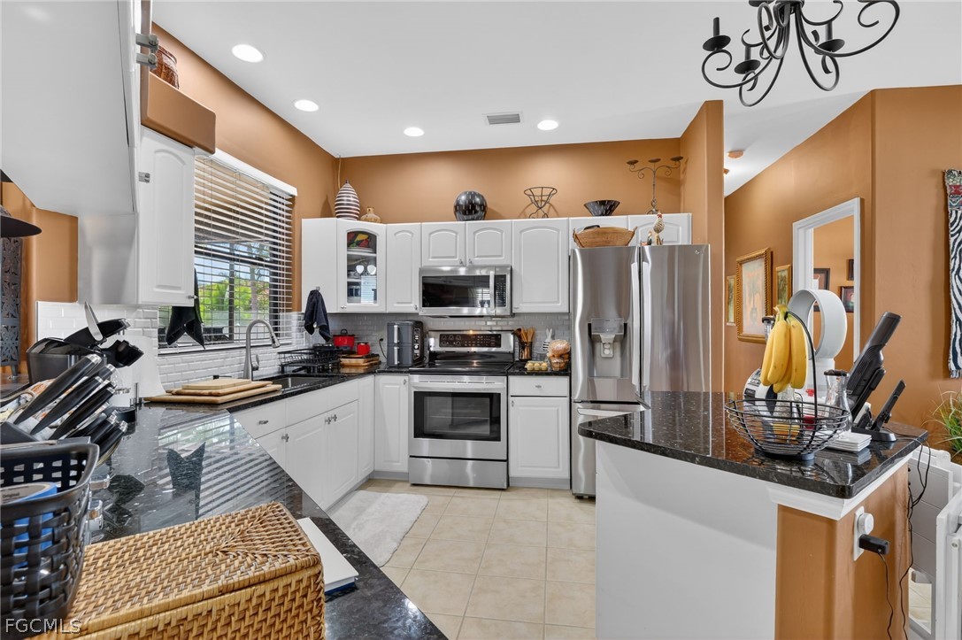 4914 Southwest 25th Court Cape Coral, FL 33914 - Photo 7 of 22 a kitchen that has a lot of cabinets a sink and appliances