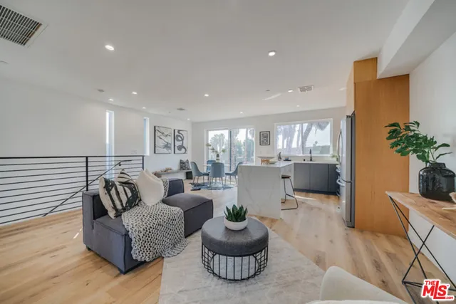 a living room with furniture potted plant and kitchen view