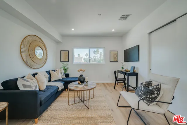 a living room with furniture a clock and a flat screen tv