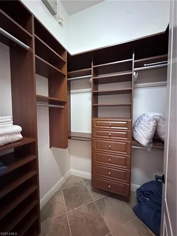 a view of walk in closet with clothes and shoes