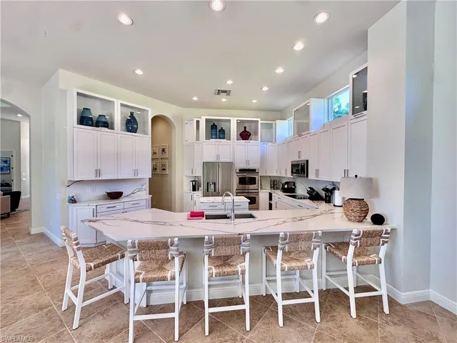 a kitchen with stainless steel appliances kitchen island granite countertop a dining table and chairs