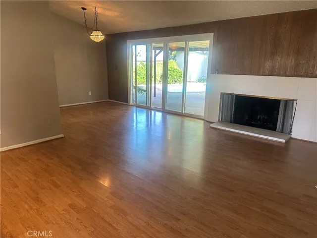an empty room with wooden floor fireplace and windows