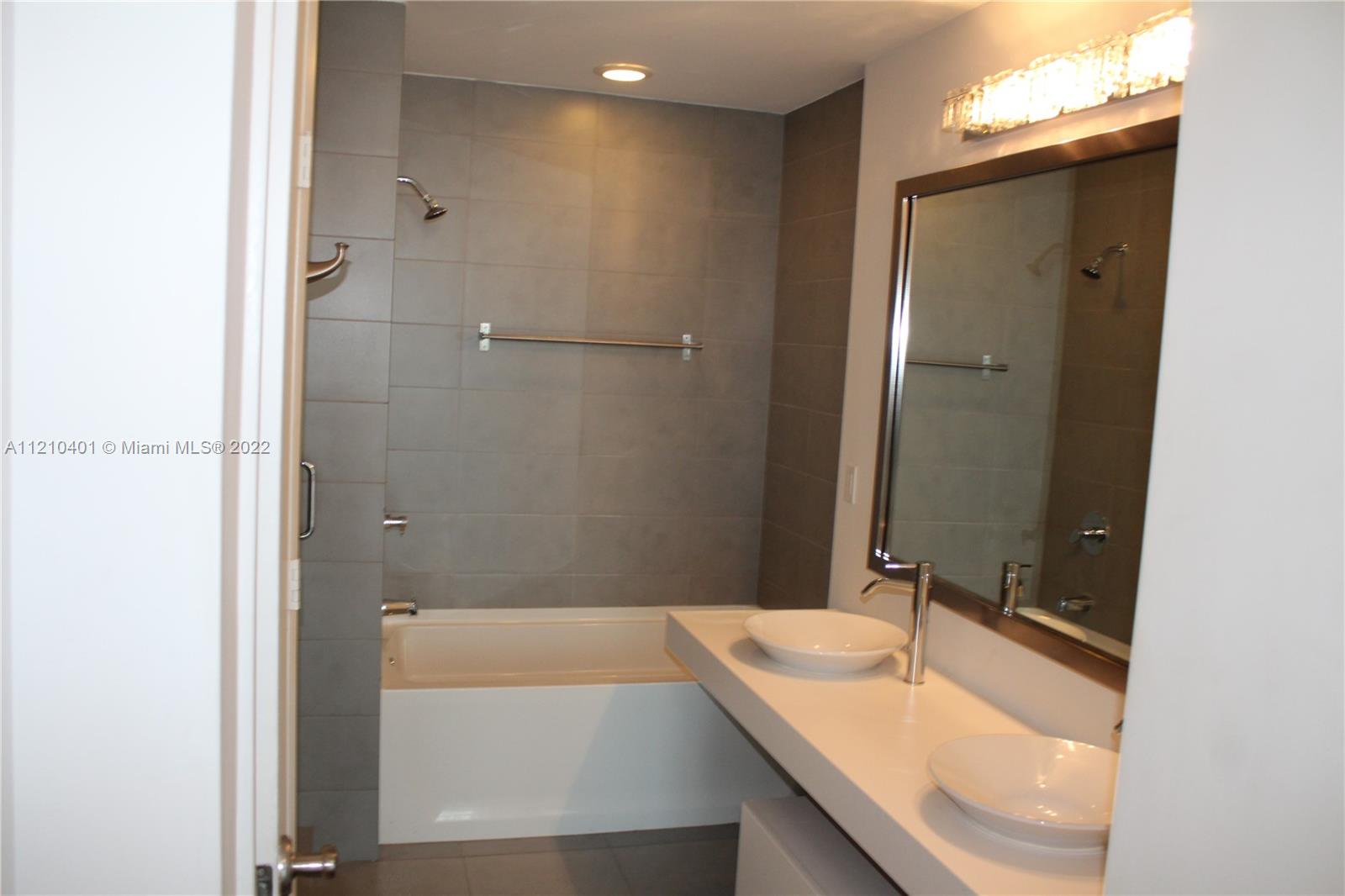 92 Southwest 3rd Street, Unit 5204 Miami, FL 33130 - Photo 18 of 20 a bathroom with a granite countertop sink and a mirror