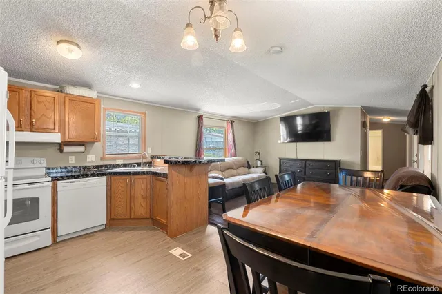 a kitchen with stainless steel appliances granite countertop a sink a stove a dining table and chairs