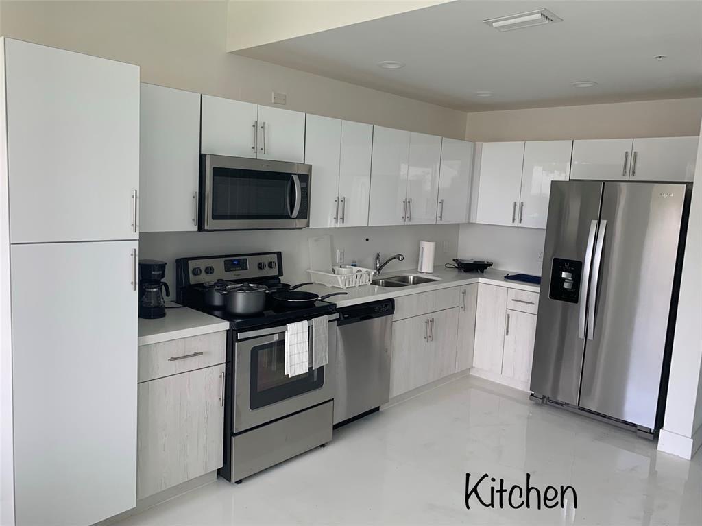 520 Foster Road, Unit 101 Hallandale Beach, FL 33009 - Photo 2 of 8 a kitchen with a sink a stove a refrigerator and cabinets