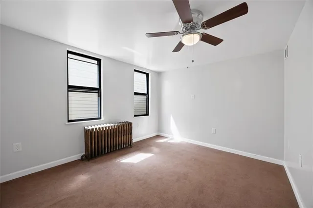 an empty room with windows and ceiling fan