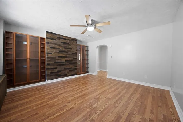 a view of empty room with wooden floor and ceiling fan