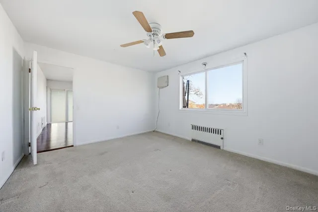 an empty room with ceiling fan and windows