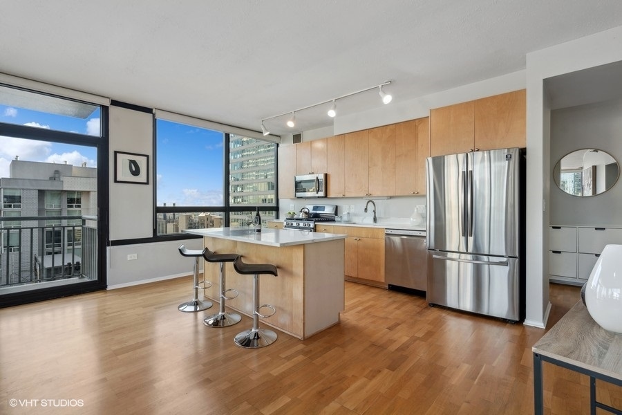 701 South Wells Street, Unit 1904 Chicago, IL 60607 - Photo 7 of 22 a kitchen with stainless steel appliances granite countertop a refrigerator a sink dishwasher a stove with wooden cabinets and floor