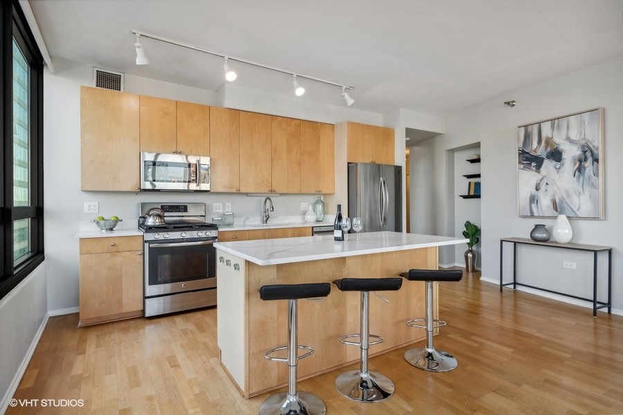 701 South Wells Street, Unit 1904 Chicago, IL 60607 - Photo 8 of 22 a kitchen with a sink cabinets and wooden floor