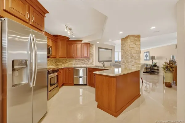 a kitchen with stainless steel appliances kitchen island granite countertop a refrigerator and a sink
