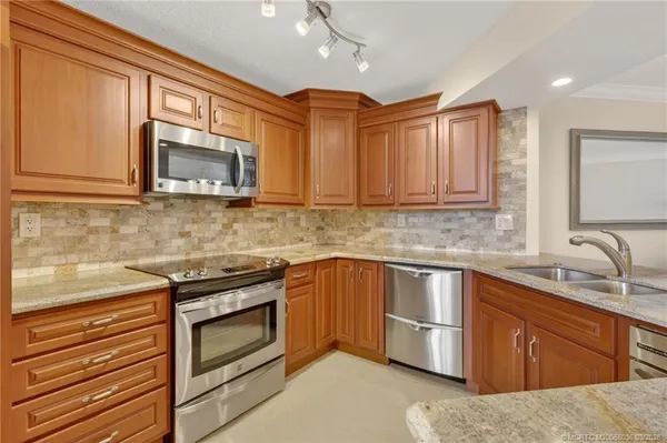 a kitchen with stainless steel appliances granite countertop wooden cabinets and a stove top oven