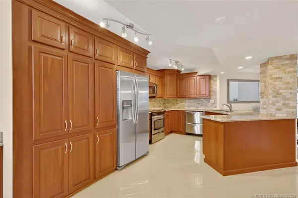 a large kitchen with stainless steel appliances granite countertop a refrigerator and a sink