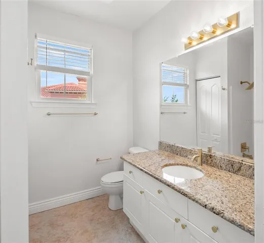 a bathroom with a granite countertop sink a toilet and a mirror