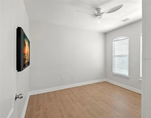 an empty room with windows and fan