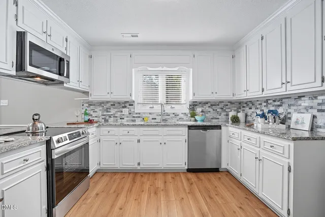 a kitchen with granite countertop cabinets stainless steel appliances a sink and window