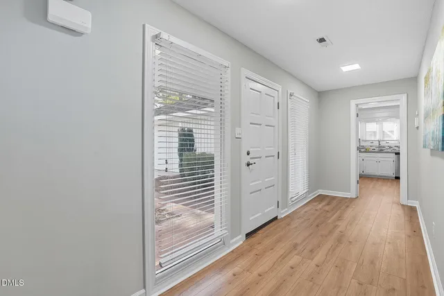 a view of a hallway with wooden floor and a bathroom