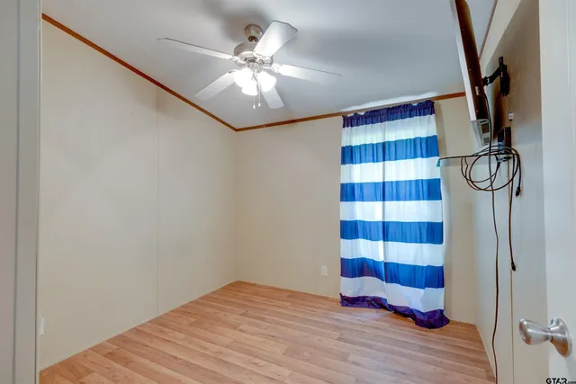 a view of empty room with wooden floor and fan