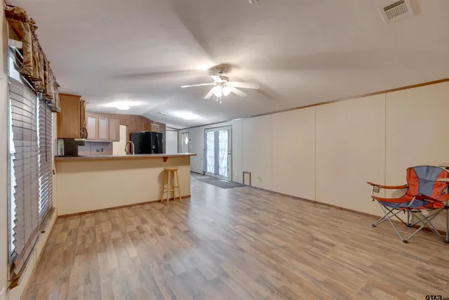 a living room with stainless steel appliances kitchen island hardwood floor and a kitchen view