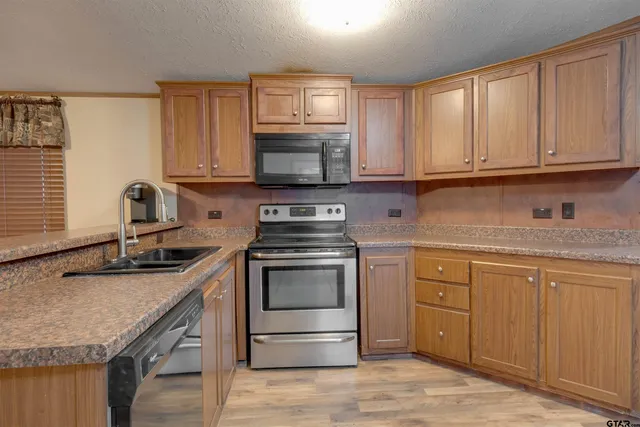 a kitchen with granite countertop a sink stove and microwave