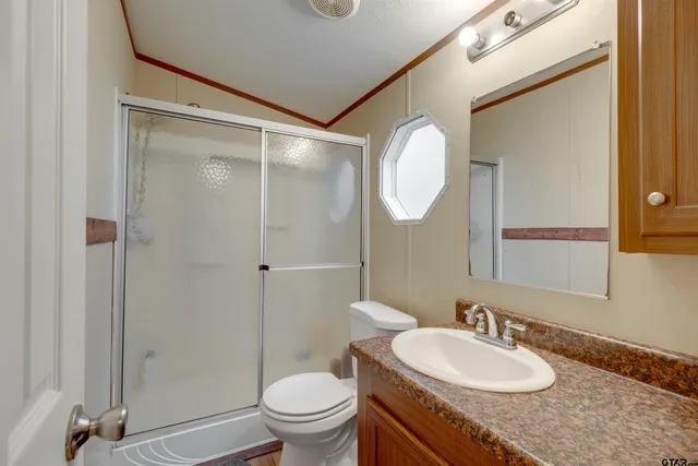 a bathroom with a granite countertop sink toilet a mirror and shower