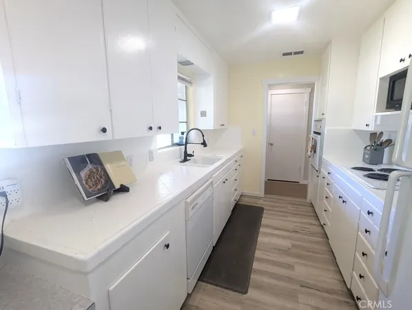 a large white kitchen with a sink a refrigerator and a stove