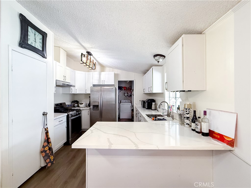 1855 East Riverside, Unit 130 Ontario, CA 91761 - Photo 22 of 62 a kitchen with stainless steel appliances granite countertop a refrigerator a oven a sink a stove and a refrigerator with wooden floor