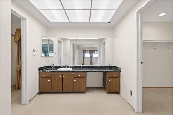a spacious bathroom with a granite countertop sink a mirror and bathtub