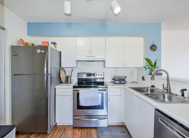 a kitchen with a refrigerator sink and white cabinets
